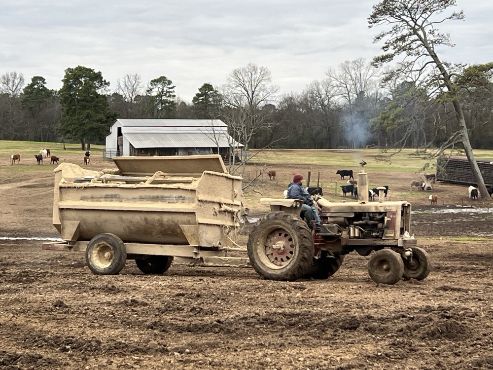 Tractor pulling a feed mixer wagon across the lot